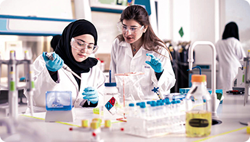 Two women in lab coats working with beakers and test tubes.